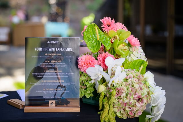 &ldquo;Your Hiptwist Experience&rdquo; sign beside a pink and green floral arrangement