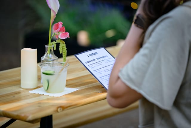 A guest reads the drinks menu beside a cocktail and a candle