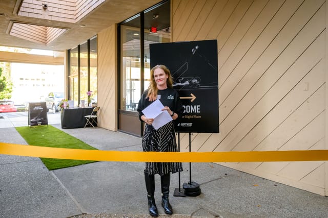 Notes in hand behind the gold ribbon at the studio entrance, just before the ribbon cutting