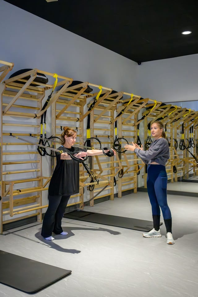 An instructor coaches a guest with suspension straps
