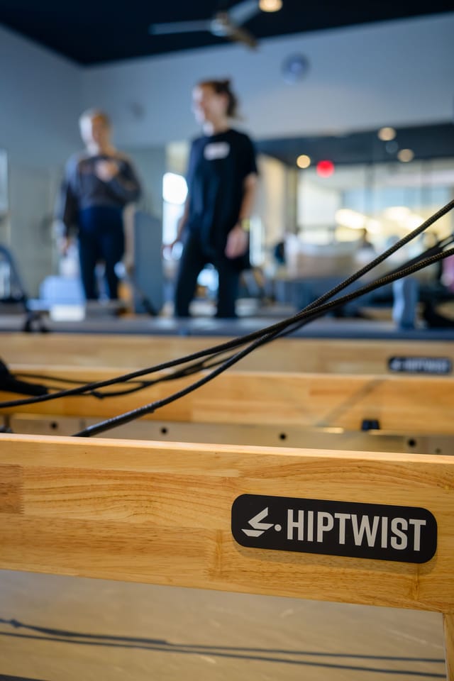 Close-up of a Hiptwist reformer with guests in the background